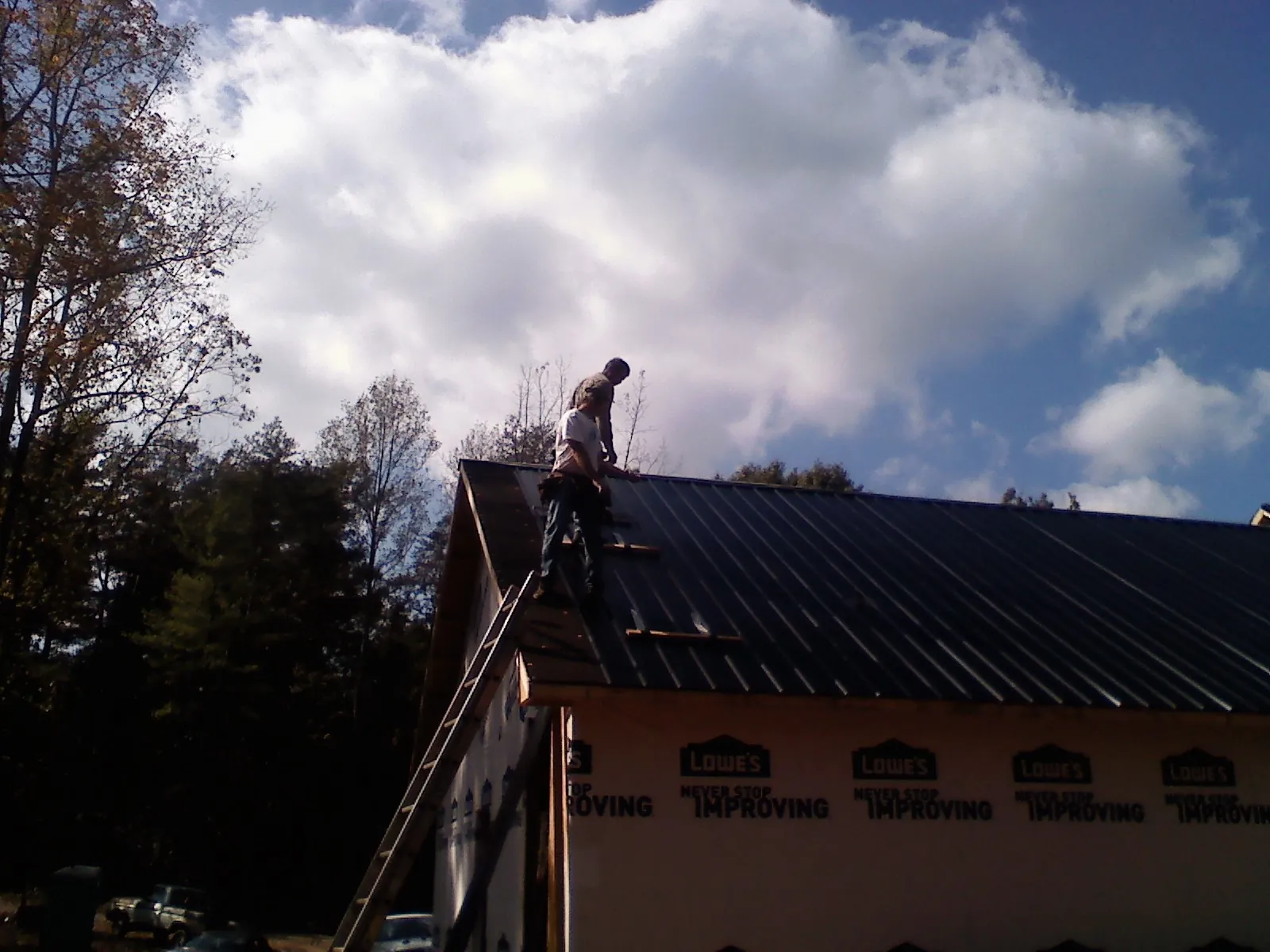 Roofer fastening dark metal panels high against a cloudy sky, from a Roof Inspection job in Mineral Springs