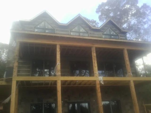 Dormers and porch framing on a large log home under construction — Roof Coating work by our crew in Mineral Springs