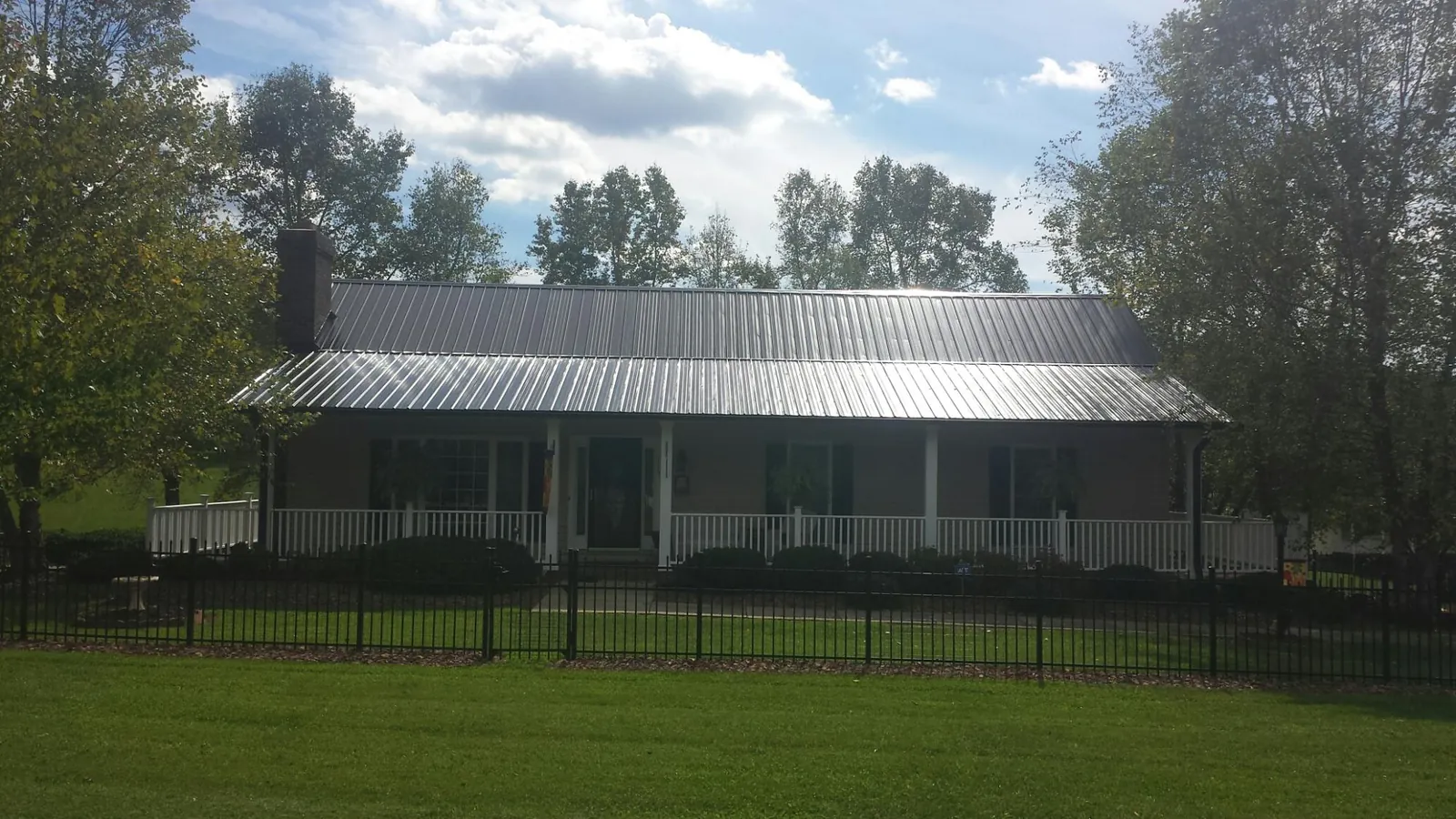 Gray metal roof on a brick ranch with a full width front porch — Gutter Guard Installation work by our crew in Mineral Springs